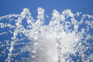 Water stream is gushing up against cloudless blue sky background