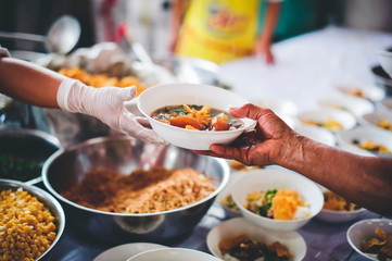 Volunteers scooping the food to share with the needy : concept of providing free food to homeless...