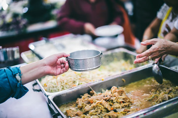 Volunteers scooping the food to share with the needy : concept of providing free food to homeless people.