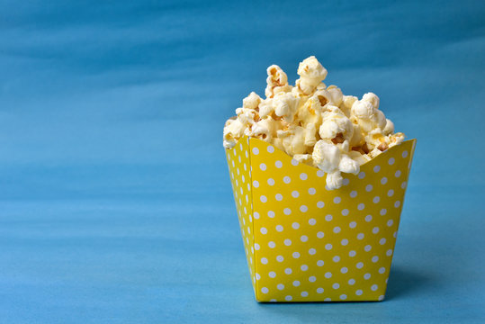 popcorn falling from paper packaging with blue background