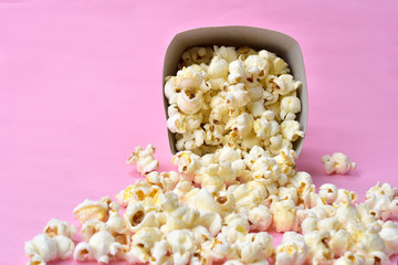 popcorn falling from paper packaging with pink background