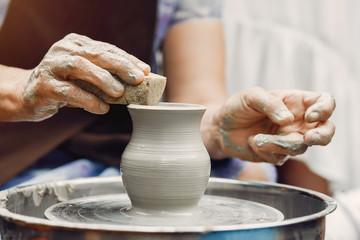 Fototapeta na wymiar Potter make a small jug. Hands of a potter at work
