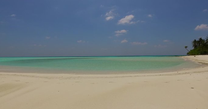 White sand of idyllic beach surrounding a calm lagoon with emerald water on a hot day in Pulau Biola island