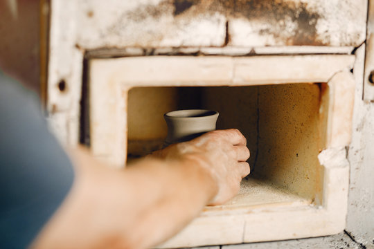 Man use a clay oven. Oven for clay. Man pust a jug inside