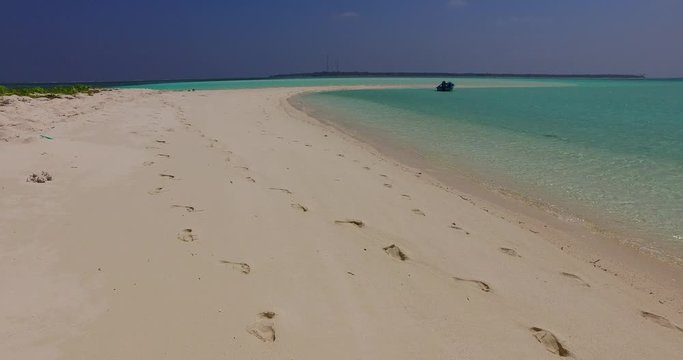 Flip flops footprints on a pristine long beach washed by clean emerald water in Malay Archipelago 