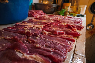 Pieces of raw meat. Seasoning meat over a background in rustic cuisine, in the foreground.