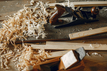 Man working with a wood. Carpenter in a white shirt. Man with a chisel