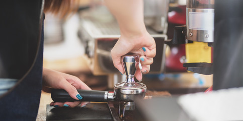 Cropped shot of professional female barista grinding fresh roasted coffee beans
