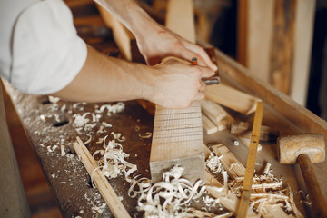 Man working with a wood. Carpenter in a white shirt