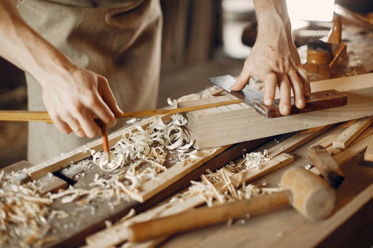 Man working with a wood. Carpenter in a white shirt