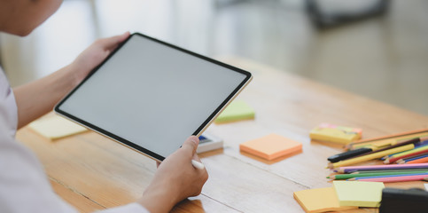 Close-up view of young male designer planing his project with tablet in his workplace