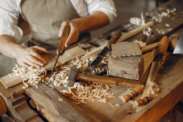 Man working with a wood. Carpenter in a white shirt