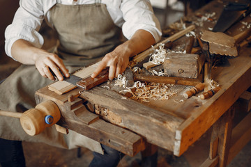 Man working with a wood. Carpenter in a white shirt
