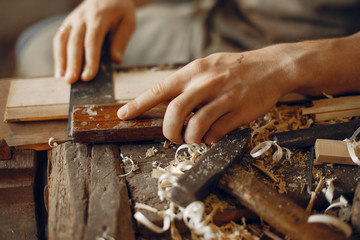 Man working with a wood. Carpenter in a white shirt