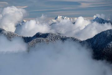 Mountains covered with fresh snow and white clouds over the peaks. Seymour Mountain Provincial Park. Ski resort in North Vancouver. British Columbia. Canada.