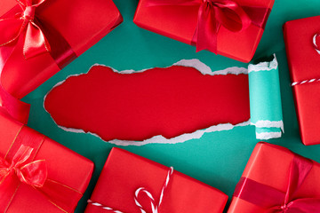Boxing day Sale Online shopping. Top view of green pastel torn paper with red gift boxes.