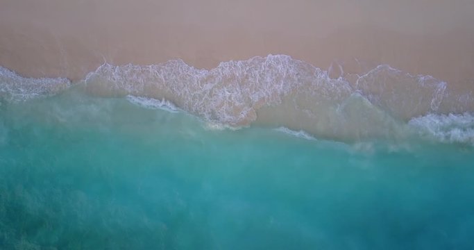 top view of blue waves at sea shore in maldives, still drone shot
