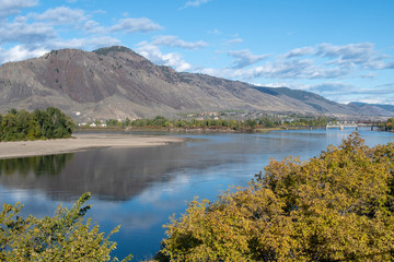 Fototapeta premium View on Mount Paul and confluence of Thompson Rivers, Overlanders Beach in Kamloops, BC. Sunny autumn day, clouds reflecting in the water.