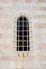 Window with grate in the brick wall of church
