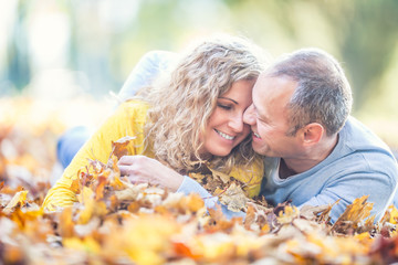 Happy senior couple lying in autumn maple leaves