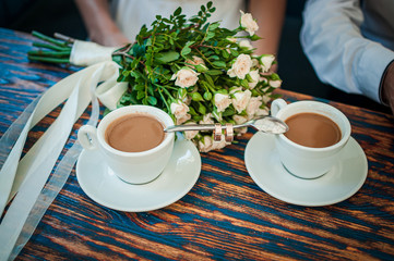 Pair of gold wedding rings on a spoon between two cups of coffee