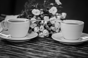Pair of gold wedding rings on a spoon between two cups of coffee