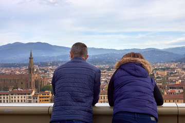 Tourists man and woman look at panorama of historical center of Florence in Italy from Piazzale Michelangelo. Back view