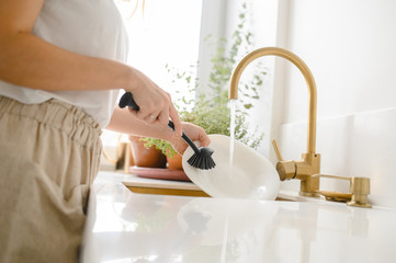 Woman washing dishes in the kitchen. Close up of woman hand. Housewife clean dishes