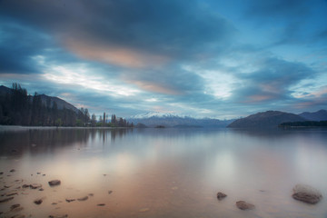 Lake wanaka during sunset in long exposure shot with snowcap mountain in the background.New Zealand road trip.