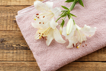 Obraz na płótnie Canvas Soft terry towel with bouquet of flowers on wooden background.