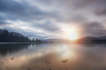 Lake wanaka during sunset in long exposure shot with snowcap mountain in the background.New Zealand road trip.