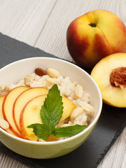 Sorghum salad with nuts and fresh peach on stone board.