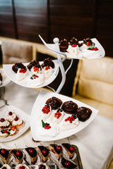 Sweet table. A plates of cakes and muffins with cream with berries. Table with sweets, candy, buffet. Dessert table for a party goodies for the wedding. Close up. 