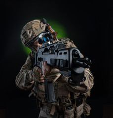 a male soldier in military clothes with a weapon on a dark background