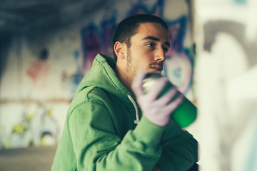 Street artist painting colorful graffiti on a wall.