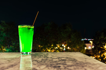 delicious green cocktail on a marble table at night.