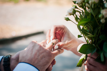 Groom puts on the wedding ring on the finger of the bride