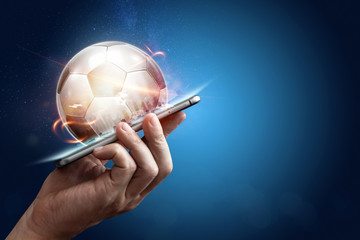 Smartphone in hand with a 3D soccer ball on a blue background. Bets, sports betting, bookmaker....
