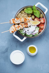 Greek souvlaki bowl with addition of quinoa and vegetables, flatlay over grey concrete background, studio shot