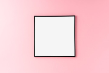 Empty photo frame hanging on pink wall. Mockup