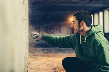 Street artist painting colorful graffiti on a wall.