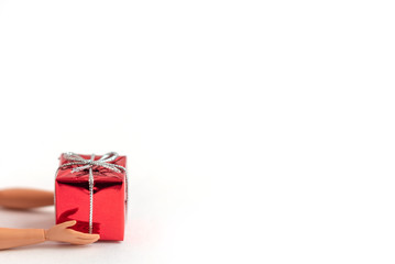 red gift box in the hands of a doll on a white background