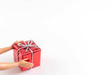 red gift box in the hands of a doll on a white background