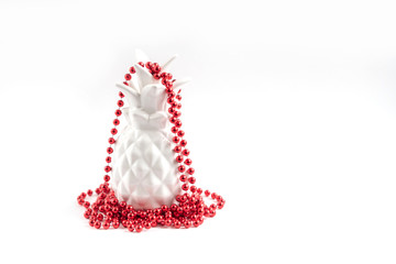 white pineapple in red Christmas beads. alternative Christmas tree. minimal creative concept. 