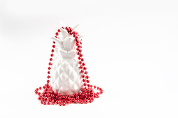 white pineapple in red Christmas beads. alternative Christmas tree. minimal creative concept. 