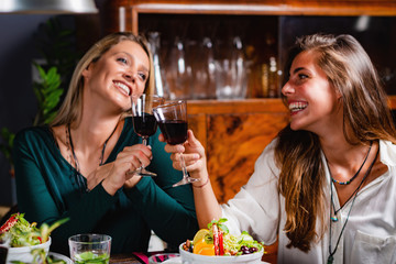 Healthy Eating. Female Friends in Vegetarian Restaurant Eating, Drinking Wine and Having Fun.