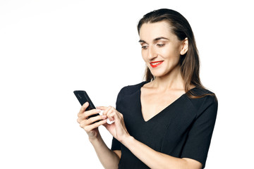 Business woman (fatal woman) in a black dress with red lipstick looks at her phone, isolated on a...