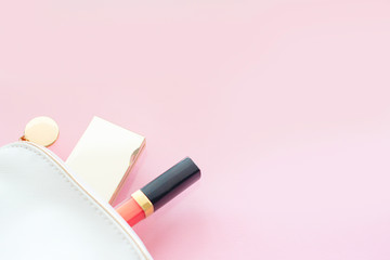 Cosmetic bag with a minimum set of cosmetics on a pink background. Minimalism concept. 