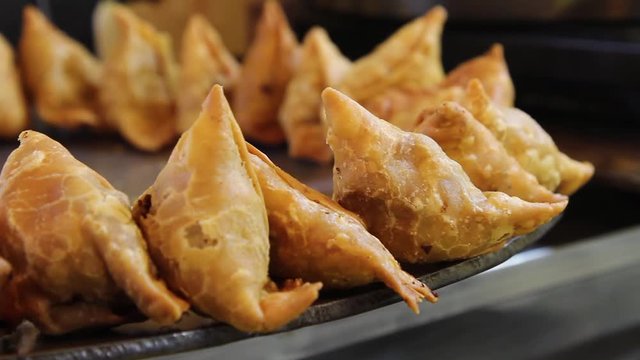 Closeup footage of popular Indian fast food snack, Samosa, a fried or baked dish with a savoury filling, such as spiced potatoes, onions, peas, or lentils. It is served with Chutney or Pav, loaf bread