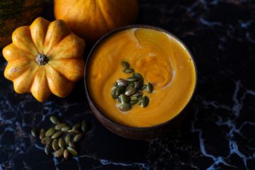 pumpkin cream soup and pumpkins on a dark marble background